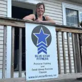 Ursula, owner of Blue Star Fitness in front of the business's signage.