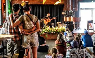 a couple looks on as a musician plays guitar in the background