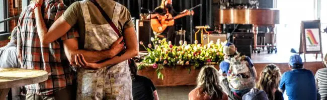 a couple looks on as a musician plays guitar in the background