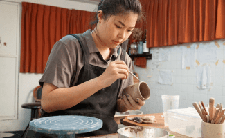 Woman creates a hand thrown vase in a pottery studio