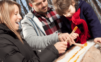 a smiling family enjoys sugar on snow together