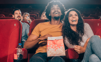 people sit in red movie theatre seats enjoying a show