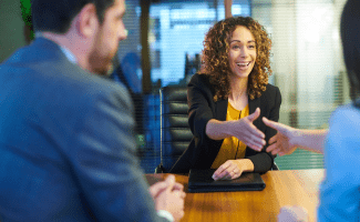 a woman enthusiastically reaches out to shake hands with another person.
