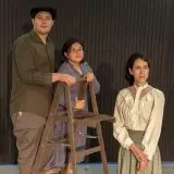 three actors pose with a wooden ladder while looking ominously into the distance
