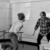 black and white image of four adults playing around in a classroom setting