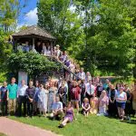 summer campers pose outdoors on and around a small building
