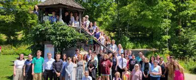 summer campers pose outdoors on and around a small building