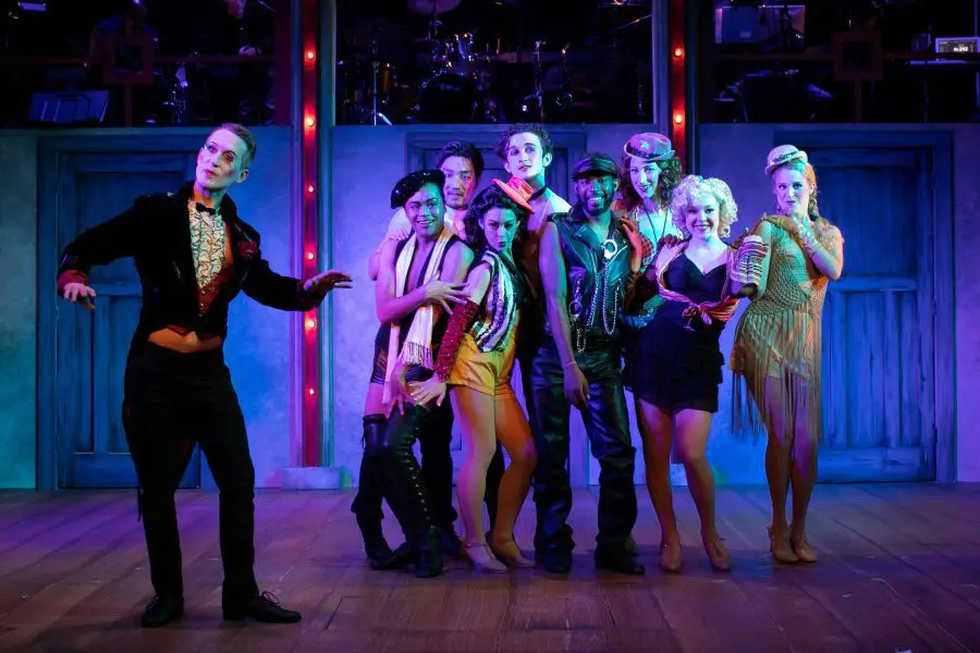 cabaret cast poses on stage in dark blue light