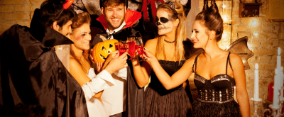 20-somethings in costume and face paint cheers to a toast