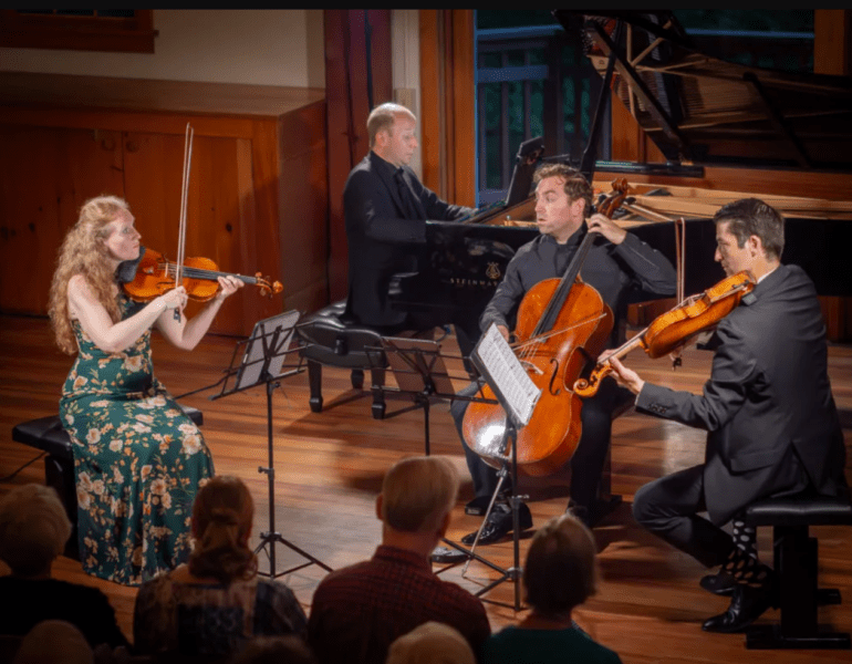 a string quartet performs, looking engagingly at one another