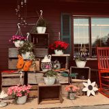 picture of a portch with apple crates, flower pots, and other decor related to christmas.