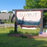 wooden summit winery road sign in lush green weather