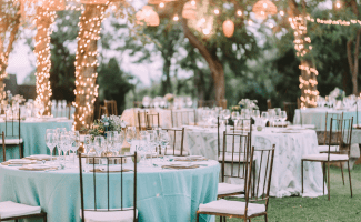 an outdoor setting with elegant chairs, tables, and fairy lights